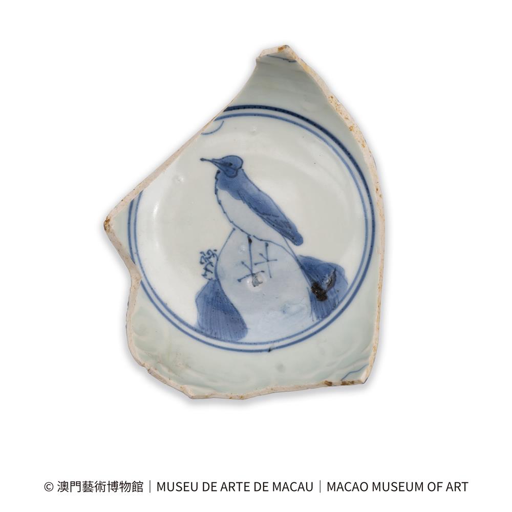 <div>青花鳥立山石紋碗標本<span style="white-space: pre;"> </span></div>
<div>明<span style="white-space: pre;"> </span></div>
<div>殘高3.6釐米 足徑6釐米</div>
<div>澳門藝術博物館</div>
<div> </div>
<div>弧腹,圈足底。外壁為一周纏枝蓮紋,內底為鳥立山石紋。內壁有模印花卉紋飾。</div>
<div>鳥立山石紋為明代中晚期外銷瓷碗中內底部位的典型紋飾,尤其在克拉克類開光青花瓷碗中,外壁及內壁配合以開光裝飾。在澳門聖保祿學院遺址及北灣一帶都發掘出土或採集有大量具有此類裝飾的標本,在日本平戶等海外遺址也有較多發現。</div>